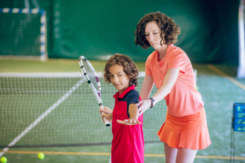 mother teaching her child tennis